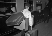 166700 Afbeelding van een kruier tijdens het inladen van de bagage in een trein (Pullman) langs het perron van het ...